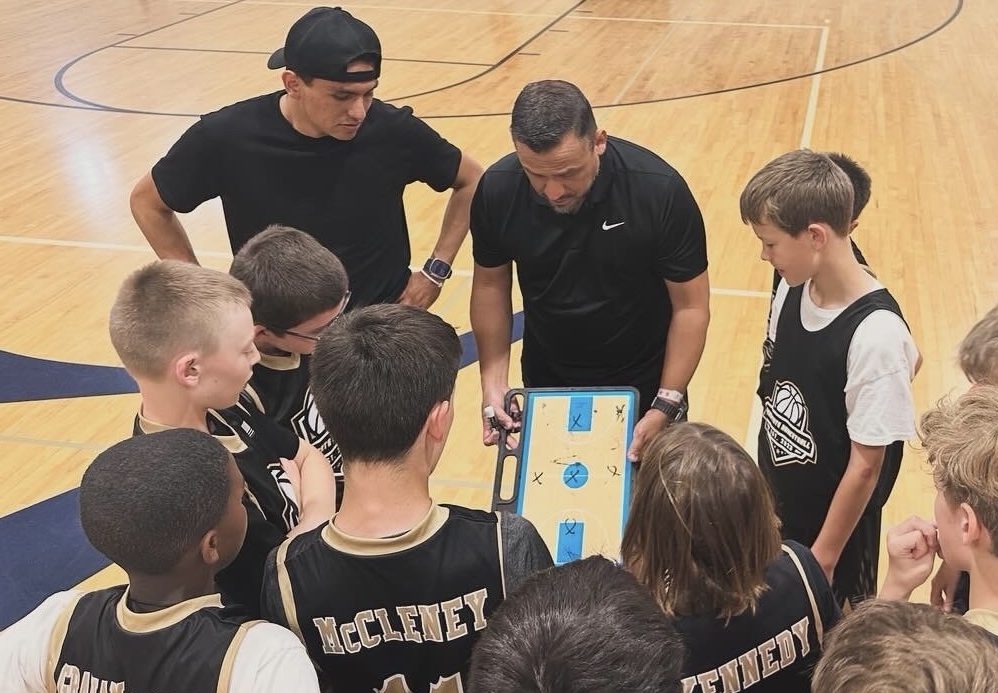 Coaches discussing strategy with a group of young basketball players.